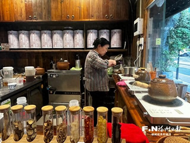 一家中草药茶饮店内，75岁的杨四姐正忙着给客人热凉茶。记者 沐方婷 摄