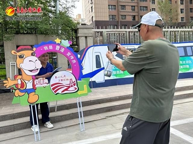 　　群众正在“普法小火车”和照相板前合影打卡。记者饶俊华摄