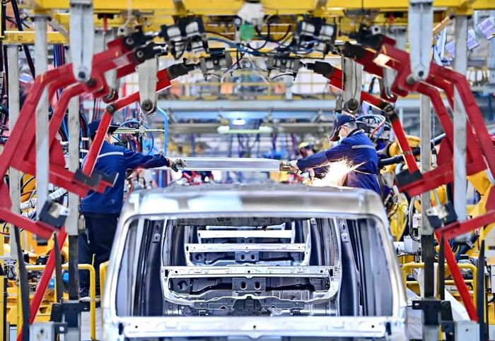 2023年12月25日，江西省赣州市，工人在冲焊生产线上焊接组装出口南美的新能源电动汽车 图自东方IC