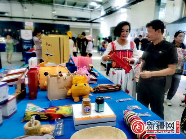 尉犁县带来4大类产品，有罗布老人系列、罗布麻茶等系列产品。图为工作人员正在向游客介绍旅游产品。