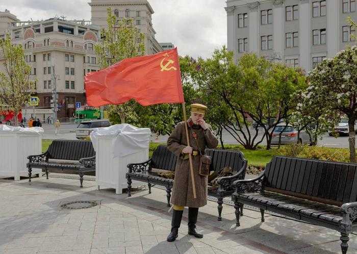 当地时间5月9日，在莫斯科举行的胜利日庆祝活动上，一名男子身着二战时期的苏联制服，手持苏联国旗（图源：《纽约时报》）