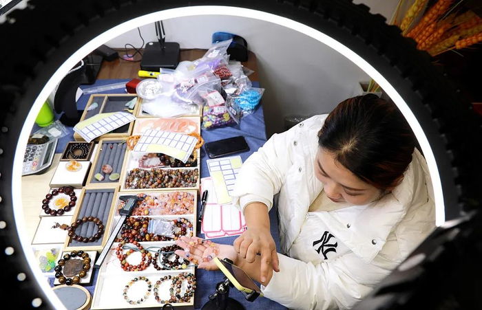 江苏省连云港市，在东海县一水晶电商中心内，工作人员在通过手机进行直播卖货/图源：视觉中国