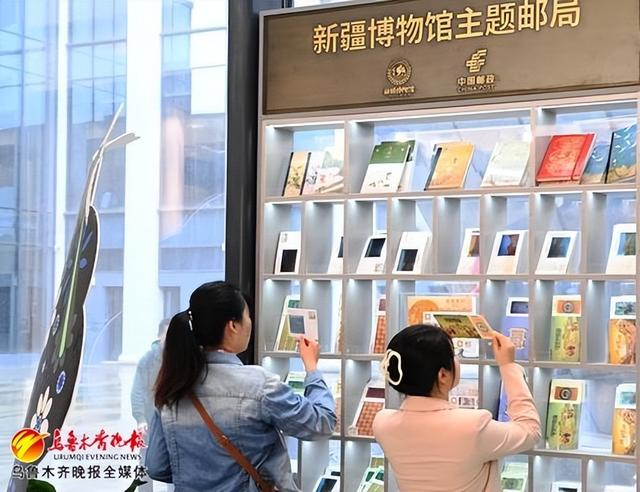 5月21日,在新疆博物馆主题邮局,来自湖南的游客正在挑选新疆特色系列