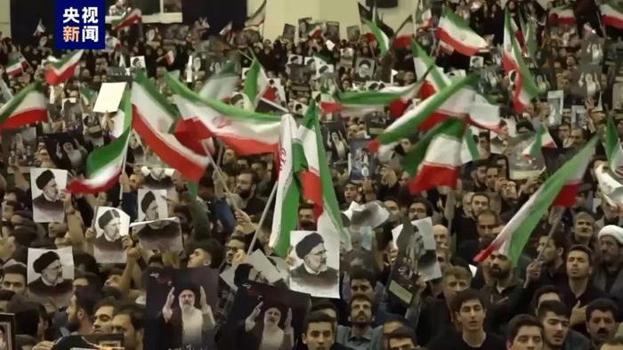 人们表情严肃,很多民众手持鲜花和莱希画像,以此缅怀总统莱希.