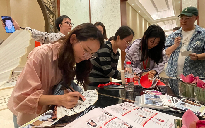 今年4月，女子围甲联赛期间，棋手们在折扇、照片上签名。  新京报记者 孙海光 摄