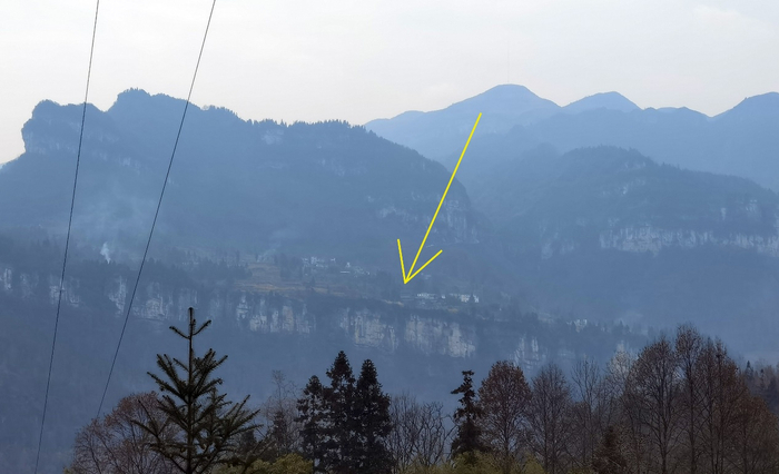 李再勇的老家，既在悬崖之上，也在悬崖之下。图中箭头所指地，即为李再勇的出生房屋所在地。程维/摄影