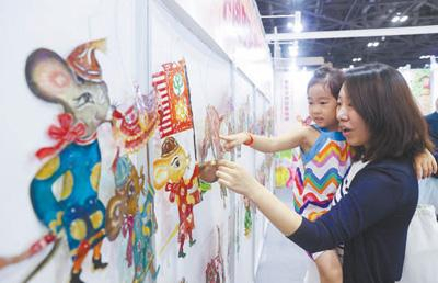 家长与孩子在首届中国（北京）动画周上观看展出的皮影。 陈晓根摄