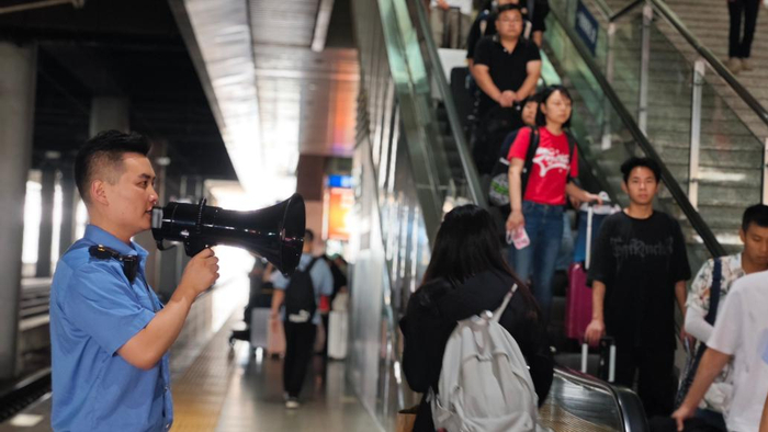 合肥南站客运员做好站台扶梯引导工作。 费莹莹 图