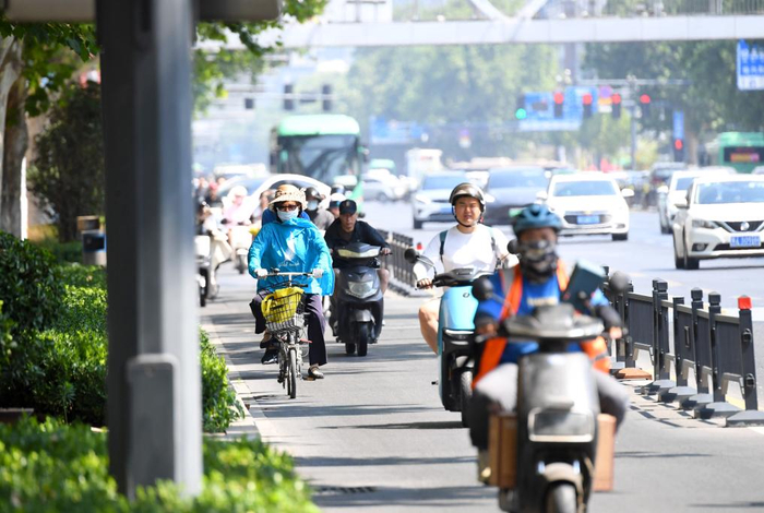 6月11日，市民骑车经过郑州市金水区花园路。 新华社记者 郝源 摄