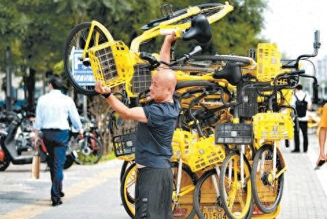 在地铁魏公村站站口，一名共享单车运维员冒着高温工作。本报记者 和冠欣 摄