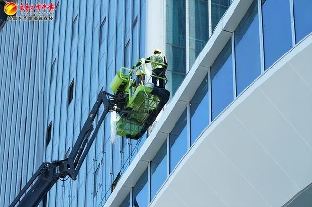 　　6月20日，在白鸟湖临港工业产业园综合服务中心项目建设现场，工人正在完善外立面。记者唐红梅摄
