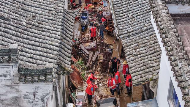 2024年6月21日，在黄山市歙县徽城镇渔梁社区，工作人员在清理过水街道。新华社 图