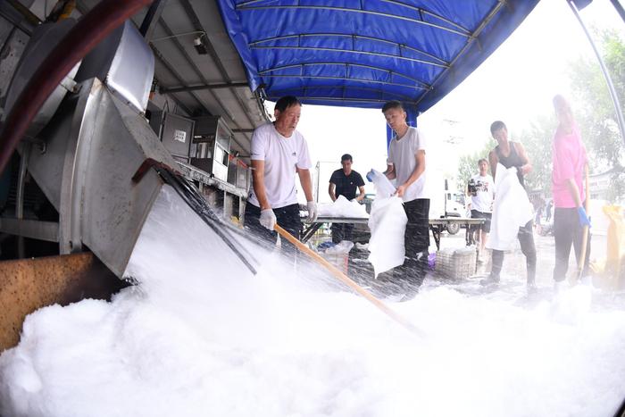 6月22日，北京新发地市场，制冰场车间外的碎冰机将冰块破碎为冰渣，装入冰袋供商户使用。  新京报记者 陈琳 摄