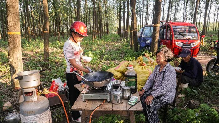 7月6日，湖南省岳阳市华容县团洲乡团西村，女儿和父母在露天的居住点做晚饭。