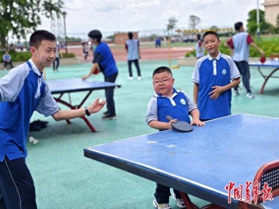 5月,四川泸州,游瑞恩(中)与同学在体育课上打乒乓球