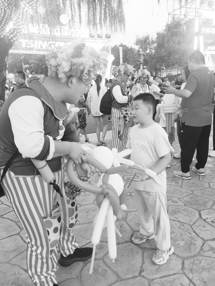 　　图为文旅小镇里“小丑”正在为小朋友送气球。