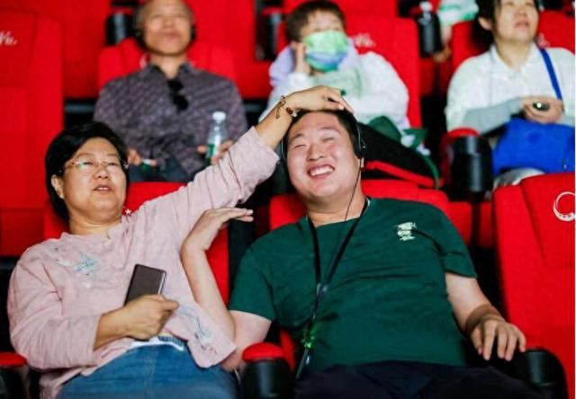 视障观众佩戴耳机接收器，和家人同“看”电影《抓娃娃》。主办方供图