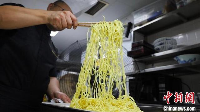 四川青年厨师付海勇正在用风扇吹凉碱水面条，这是制作四川凉面的必要工序。杨予頔 摄