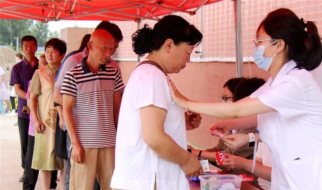 现场工作人员为预约患者贴号码牌。