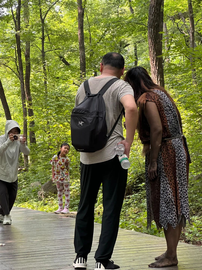 ▲游客们和野人合照。（图/新周刊 摄）