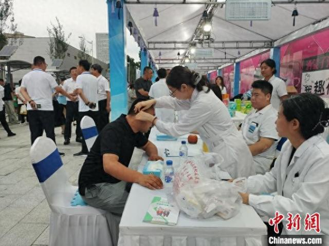 市民正在中医夜市摊位体验耳穴压豆。谭伟旗 摄