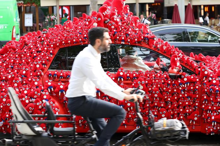 当地时间2024年7月19日，法国巴黎，“满载”奥运吉祥物弗里热的汽车驶上香榭丽舍大道。 