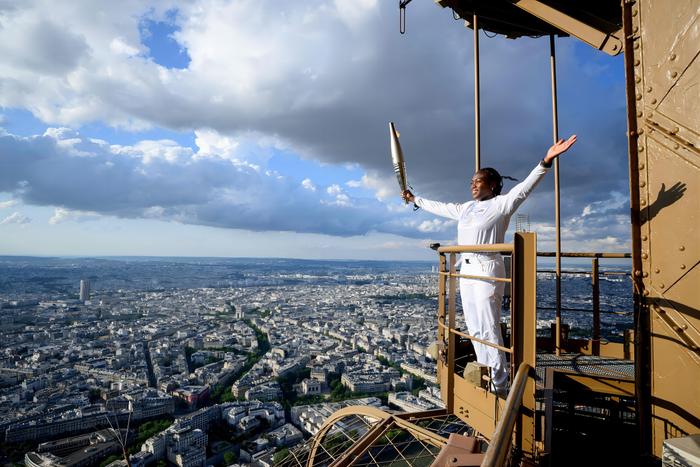 当地时间2024年7月15日，法国巴黎，法国柔道运动员克拉丽丝·阿格班尼奥手持奥运火炬在埃菲尔铁塔上传递。
