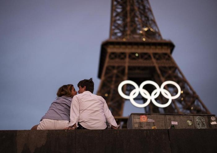 当地时间2024年6月27日，法国巴黎，一对情侣在悬挂着奥运五环的铁塔下接吻。