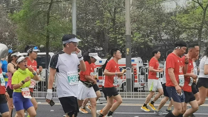 图为马拉松比赛中跑者在补给点补充能量。