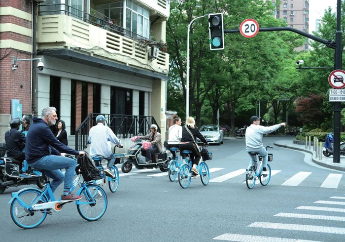 2024年4月27日，上海静安区石门二路，几名外国人骑着共享单车过马路