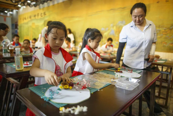 ▲2024年7月22日，北京，御道造物坊，小朋友在研学老师指导下制作团扇。图/新京报