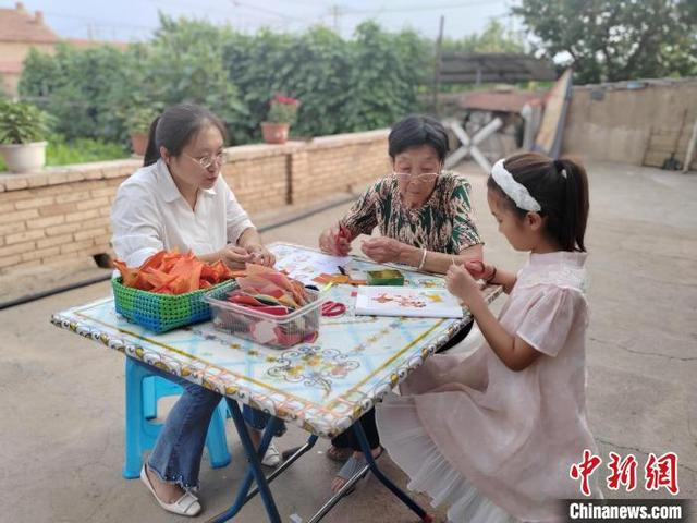 图为村民在家中庭院制作玉米皮贴画。张浩摄