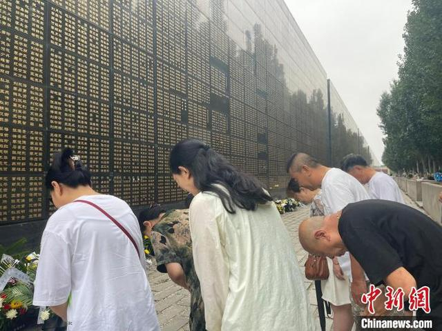 7月27日，几名唐山大地震幸存者在向墙上因地震罹难的母亲的名字鞠躬默哀。白云水 摄