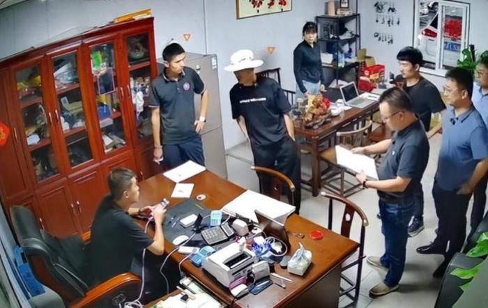 7月初，狂飙兄弟（戴白帽者）一行人来到济南某二手车商处“打假”的场景。视频截图