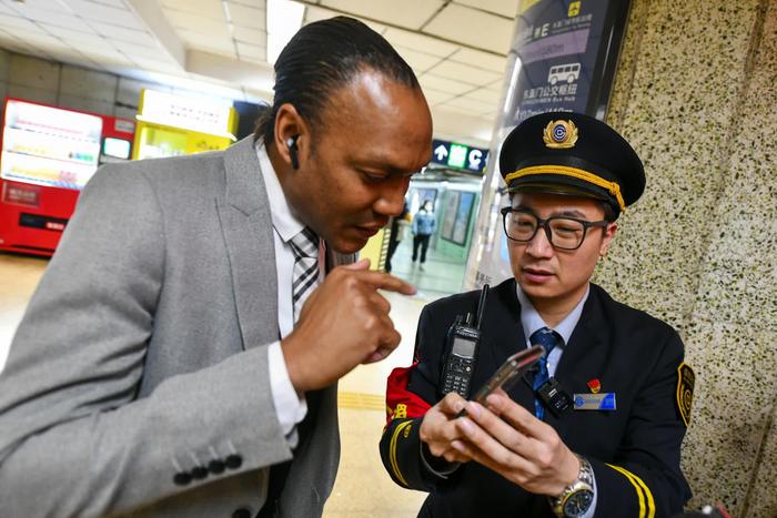在北京地铁2号线东直门站，地铁工作人员使用翻译机向外籍乘客提供服务。