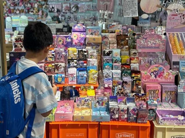 7月29日，北京东城。一动漫周边店铺内，小顾客正选购卡牌盲盒。刘胤衡/摄