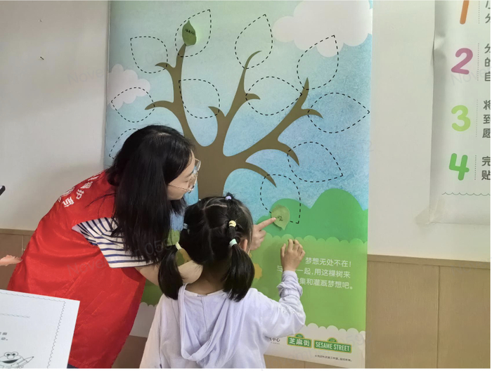 志愿者引导小朋友在“愿望树”上写下愿望
