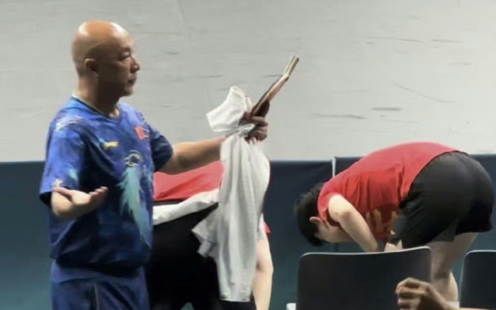 教练肖战拿着王楚钦的球拍，拍子已明显变形。  视频截图