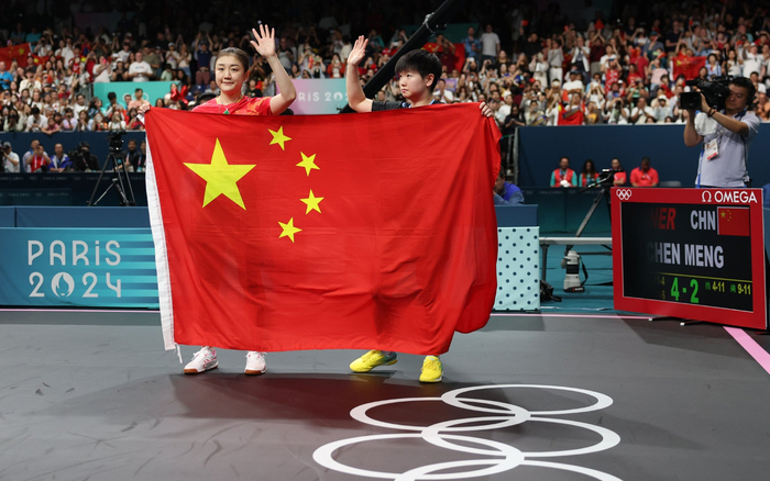 陈梦（左）和孙颖莎拿着国旗向球迷致意。 图/新华社