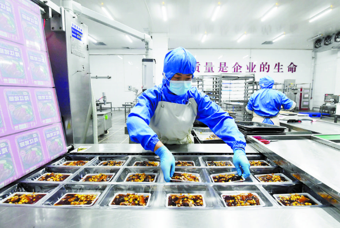 图为8月3日，在惠康食品有限公司生产车间，工人正在进行菜品加工。