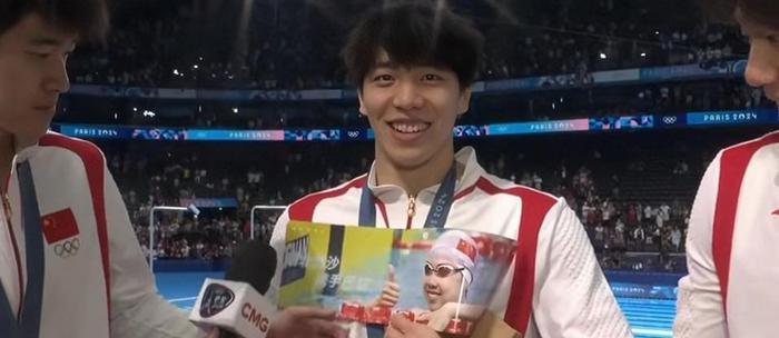 孙佳俊受访时拿着印有闫子贝和彭旭玮的手幅