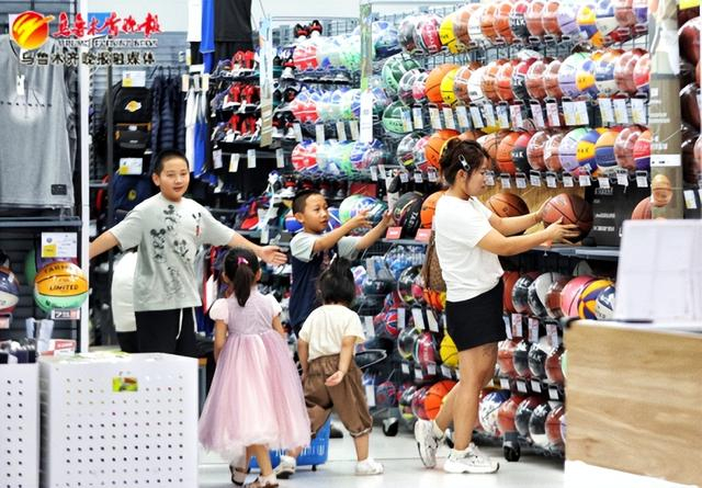 　　在位于经开万达广场的一家体育用品店，家长带小朋友选购篮球，小朋友脸上洋溢着开心的笑容。资料图片