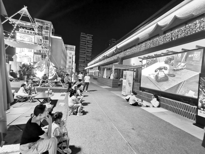 　　▲图为某特色街区里的投影设备正在播放有趣的儿童节目，吸引了家长和小朋友观看。