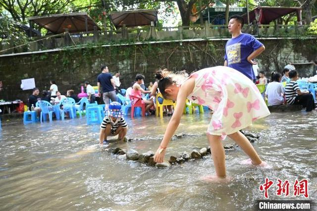8月11日，在重庆北碚金刀峡镇的偏岩古镇河滩，民众在水中进行形式多样的娱乐活动，寻觅清凉。张旭 摄 