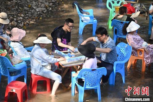 8月11日，在重庆北碚金刀峡镇的偏岩古镇河滩，民众在水中进行形式多样的娱乐活动，寻觅清凉。图为民众在水中玩麻将。张旭 摄 