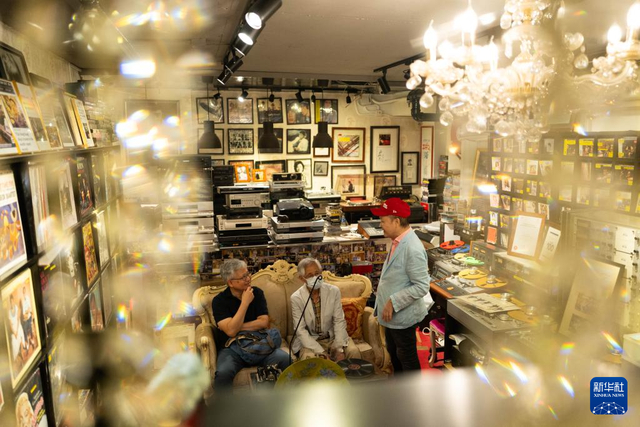 4月26日，邓汉深（右）在唱片博物馆向客人介绍音乐。新华社记者 朱炜 摄