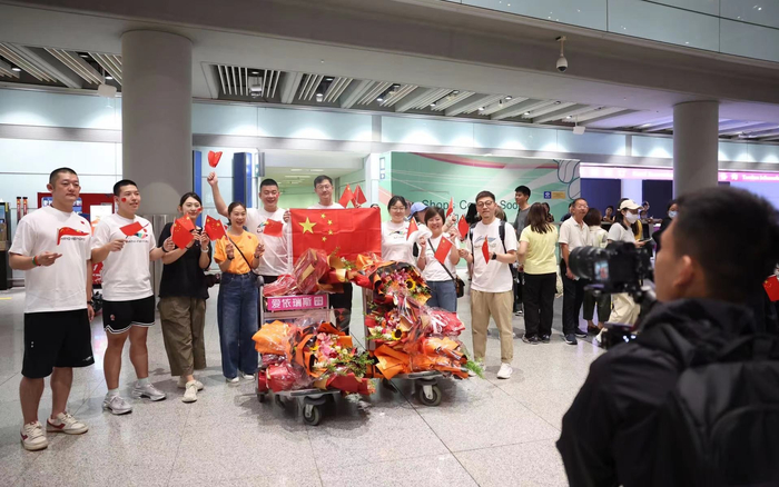 8月12日凌晨，中国乒乓球队、跳水队等队伍载誉抵京，接机人群为奥运健儿们准备了多束鲜花。新京报记者 王飞 摄