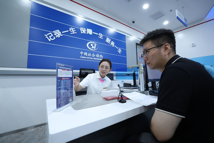 中国工商银行工作人员，正在为市民介绍北京市社银合作服务事项清单。北京市人社局供图