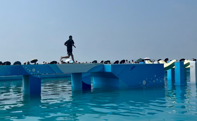 “快乐向前冲”赛道上的选手和打着伞观看比赛的观众。澎湃新闻记者 刁凡超 摄