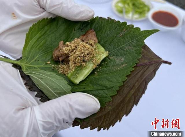 8月24日，在桦南县紫苏种植示范园，参观嘉宾品尝特色美食紫苏叶包烤肉。 刘璐 摄